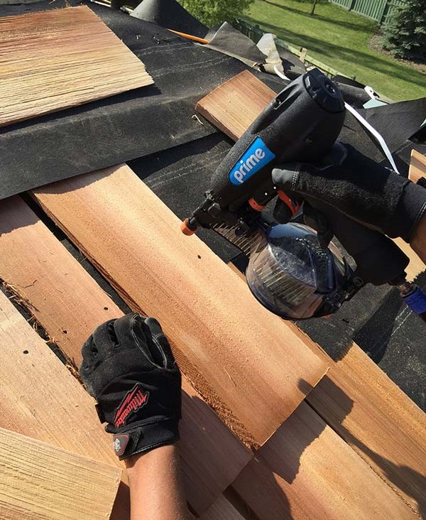 Roofing crew fastening wood roof decking with a nail gun